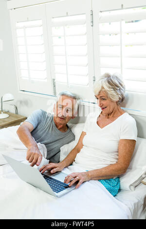 Senior couple using laptop on bed Stock Photo