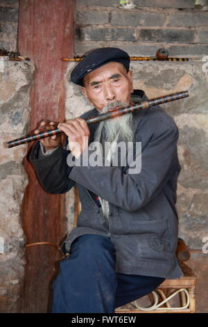 Elderly Chinese man playing a dizi, a Chinese flute in Shigu, near the first bend of the Yangtze River, China Stock Photo