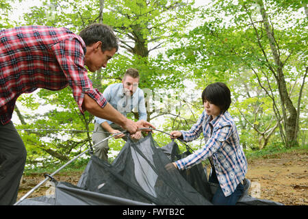Multi-ethnic group of friends putting up a tent at a camp site Stock Photo