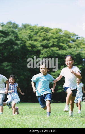 Japanese kids running in a city park Stock Photo