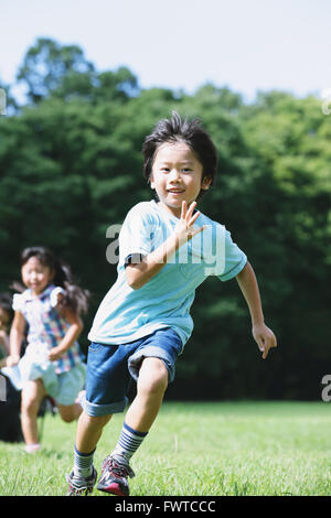 Japanese kids running in a city park Stock Photo