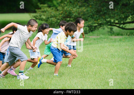 Japanese kids running in a city park Stock Photo