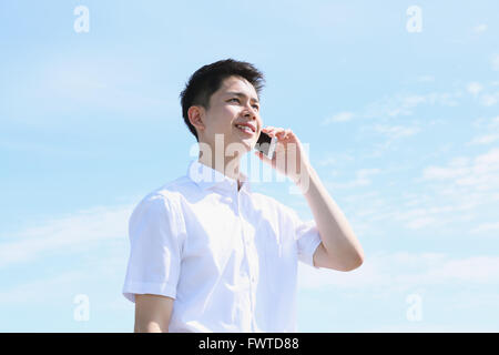 Young Japanese man on the phone by the sea Stock Photo