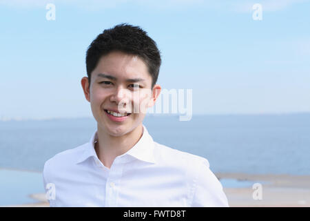 Portrait of young Japanese man by the sea Stock Photo