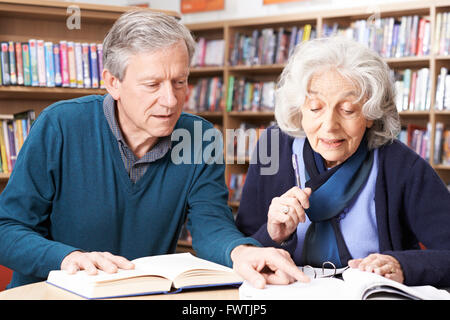 Mature Student Working With Teacher In Library Stock Photo