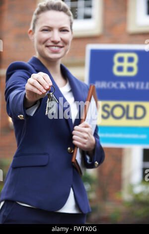 Female Realtor Standing Outside Residential Property Holding Keys Stock Photo