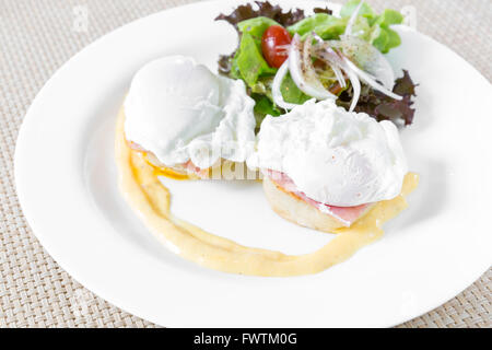 Eggs Benedict- toasted English muffins, ham, poached eggs, and delicious buttery hollandaise sauce for breakfast Stock Photo