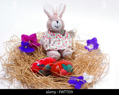 Easter bunny and eggs in nest, isolated on white background. Decorated easter egg. Ancient wooden egg. Painting. Stock Photo