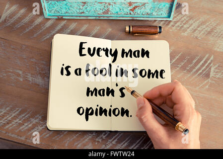 Retro effect and toned image of a woman hand writing on a notebook. Handwritten quote Every man is a fool in some man's opinion as inspirational concept image Stock Photo
