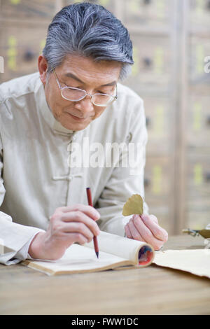 Senior Chinese doctor checking medicinal herbs Stock Photo