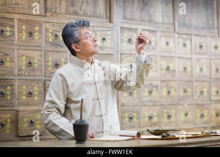 Senior Chinese doctor checking medicinal herbs Stock Photo