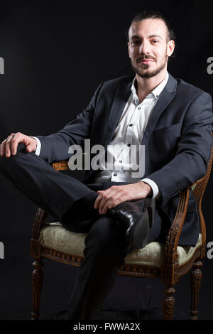 Young man sitting in a old chair one leg up Stock Photo