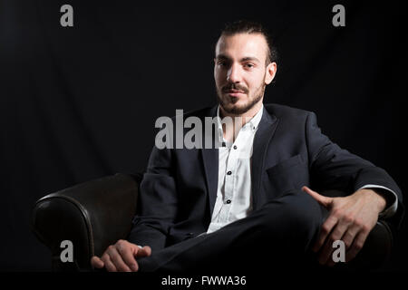 Young man sitting in a leather chair. Stock Photo