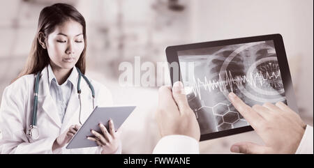 Composite image of asian doctor using tablet Stock Photo