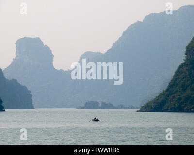 Rocky limestone islands and a small lone boat in Halong Bay, Vietnam. Stock Photo