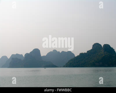 Rocky limestone islands and a small lone boat in Halong Bay, Vietnam. Stock Photo