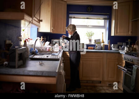 Senior Woman Making Hot Drink In Kitchen Stock Photo