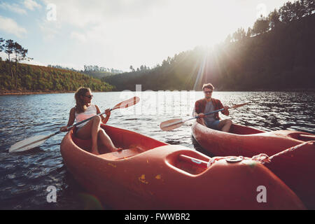 Young couple kayaking on a lake together on a summer day. Man and woman canoeing on a sunny day. Enjoying a day at the lake. Stock Photo