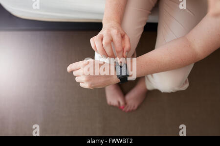Overhead shot of female hands using smartwatch. Close up image of woman using smart wrist watch in bedroom at home. Dialing a ph Stock Photo