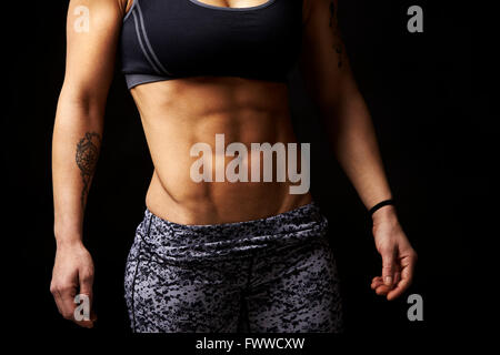 Mid-section crop shot of muscular young woman’s abs and arms Stock Photo