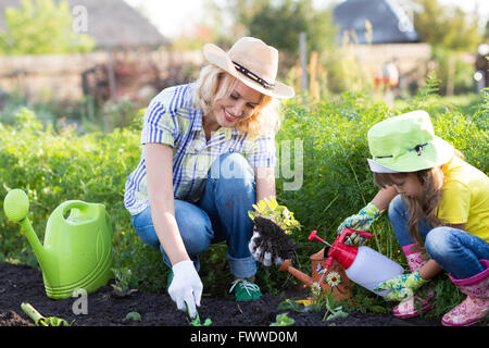 Mother and daughter watering plants in garden. Stock Photo
