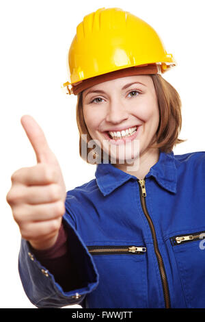 Cheering happy craftswoman in blue boiler suit holding thumbs up Stock Photo