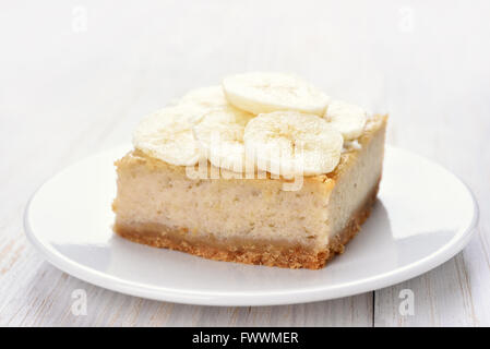 Banana cheese cake on white wooden table, close up view