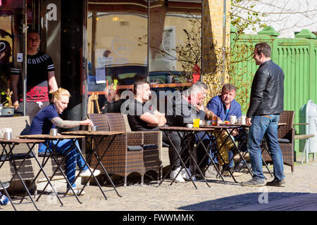 Simrishamn, Sweden - April 1, 2016: Group of men sitting outside Café Ros in town, having coffee and talking to passersby. Real Stock Photo