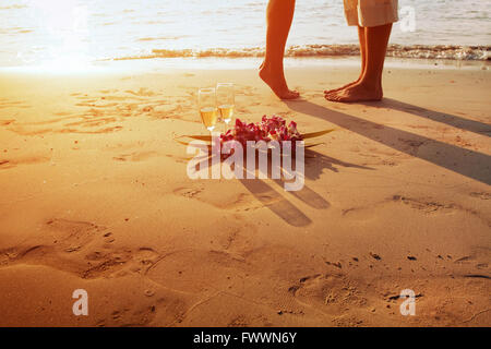 wedding on the beach, feet of romantic couple and two glasses of champagne at sunset Stock Photo