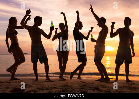 beach party, group of young people dancing, friends drinking beer and cocktails at sunset Stock Photo