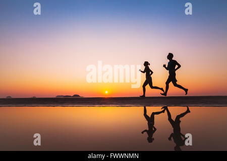 workout, silhouettes of two runners on the beach at sunset, sport and healthy lifestyle background