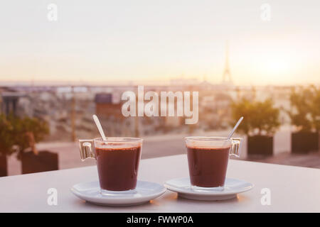 two cups of coffee or hot chocolate and Paris skyline at sunset, cafe with panoramic view of the city with Eiffel tower Stock Photo