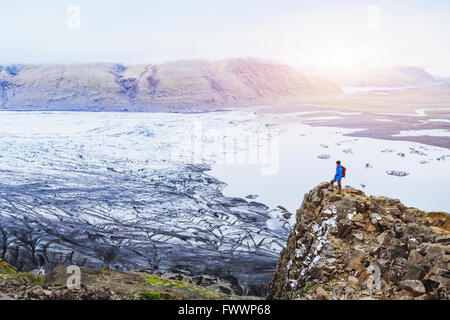 hiking in winter, backpacker enjoying panoramic landscape of glacier in Iceland at sunset in national park Skaftafell Stock Photo