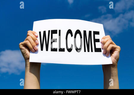 welcome concept, hands holding paper sign on blue sky Stock Photo