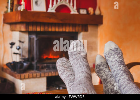 feet of couple near cozy fireplace in winter, family at home near fire Stock Photo
