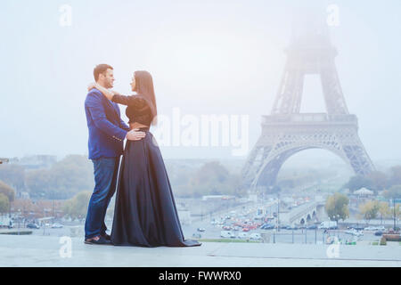 happy couple traveling in Paris, smiling man and woman posing in fancy fashion clothes on Eiffel Tower background during their h