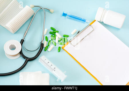 Medical conceptual picture with a stethoscope, pills, injection, gauze, adhesive plaster, bottle, empty clipboard sheet. Stock Photo