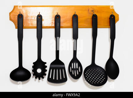 Kitchen utensils hanging on the wall with white background Stock Photo