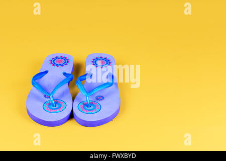 Pair of blue flip-flops on yellow background Stock Photo