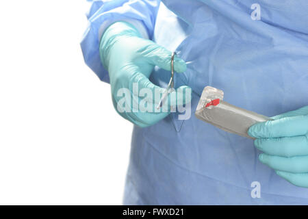 Operating room technician prepares suture for use with needle holder. Stock Photo