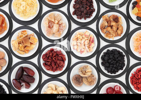 Dried fruit selection in porcelain bowls on slate rounds over white background. Stock Photo
