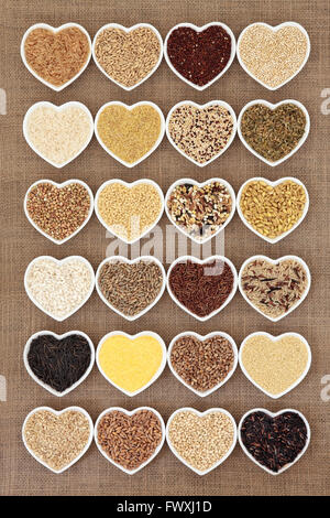 Grain and cereal food selection in heart shaped porcelain bowls over hessian background. Stock Photo
