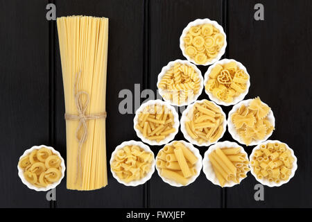 Spaghetti pasta dried food selection in a bundle and in porcelain crinkle bowls  over dark wood  background. Stock Photo