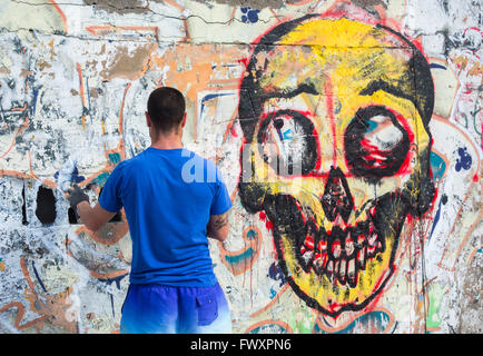 Graffiti artist spraying over old graffiti on wall in Spain Stock Photo