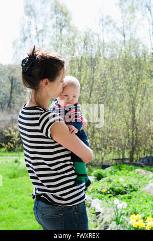 Sweden, Ostergotland, Vikbolandet, Woman carrying and kissing baby boy (6-11 months) Stock Photo