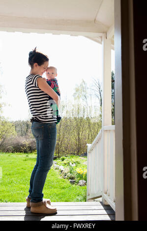 Sweden, Ostergotland, Vikbolandet, Woman carrying baby boy (6-11 months) Stock Photo