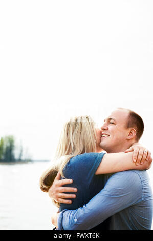 Sweden, Gastrikland, Sandviken, Smiling couple hugging with lake in background Stock Photo