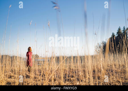 Finland, Varsinais-Suomi, Young woman standing in field in sunlight