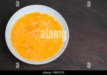whisking eggs in bowl on wood background Stock Photo