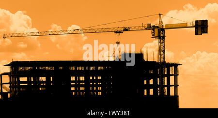 Silhouette of construction workers on scaffold working under a hot sun Stock Photo